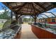Outdoor kitchen under a covered structure with granite countertops, stainless steel grill, sink, and ample cabinet space at 3934 Se 110Th St, Belleview, FL 34420