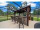 Outdoor kitchen with bar seating, stone accents, a grill, and views of the lush backyard and beautiful blue skies at 3934 Se 110Th St, Belleview, FL 34420