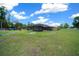 Spacious backyard featuring a screened pool enclosure and ample green space on a sunny day at 3934 Se 110Th St, Belleview, FL 34420
