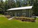 Unique green home featuring a metal roof, inviting porch with seating, and well-maintained landscaping at 400 Se 90Th St, Ocala, FL 34480