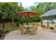 Outdoor dining area with a table and four chairs, shaded by an umbrella, surrounded by lush landscaping and a charming yard at 400 Se 90Th St, Ocala, FL 34480
