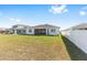View of the spacious backyard with a white fence, green grass and a covered patio at 6342 Sw 77Th Ave, Ocala, FL 34474