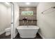 Bathroom with a standalone tub beneath a window and a toilet in an adjacent room at 6600 Sw 109Th Ln, Ocala, FL 34476