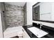 Bathroom featuring a shower-tub, a gray tiled accent wall and a dark granite vanity at 6600 Sw 109Th Ln, Ocala, FL 34476