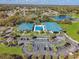 Aerial view of the clubhouse, pool, and parking area, surrounded by lush landscaping and a lake at 6758 Sw 114Th Street Rd, Ocala, FL 34476