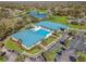 Aerial view of the clubhouse, pool, and parking area, surrounded by lush landscaping and a lake at 6758 Sw 114Th Street Rd, Ocala, FL 34476