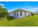 Backyard featuring a well-maintained lawn, a door, and windows with gray trim on a bright, sunny day at 6758 Sw 114Th Street Rd, Ocala, FL 34476