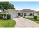 Well-maintained single-story home featuring an attached garage, landscaped front yard, and curved brick driveway at 6858 Sw 111Th Loop, Ocala, FL 34476