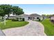 Well-maintained single-story home featuring an attached garage, landscaped front yard, and curved brick driveway at 6858 Sw 111Th Loop, Ocala, FL 34476