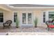 Covered front patio features decorative glass front doors, tiled flooring and two cushioned wicker chairs on each side at 6858 Sw 111Th Loop, Ocala, FL 34476