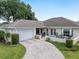 Charming single-story home featuring a brick-paved driveway, attached garage, and cozy front patio for outdoor relaxation at 6858 Sw 111Th Loop, Ocala, FL 34476