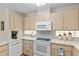 Kitchen features bright cabinets, white appliances, and tiled flooring at 6858 Sw 111Th Loop, Ocala, FL 34476