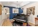Piano room boasts blue accent wall, chandelier, gleaming piano, and hardwood floors at 6858 Sw 111Th Loop, Ocala, FL 34476
