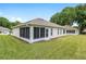 A screened-in patio adjacent to a spacious lawn showcasing the home's exterior at 6858 Sw 111Th Loop, Ocala, FL 34476