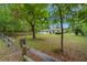 A home with a charming white exterior situated on a spacious lot with mature trees and a rustic wooden fence at 8130 Sw 209Th Court Rd, Dunnellon, FL 34431