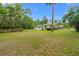 Spacious front yard featuring a well-maintained lawn and mature trees, with a charming home in the background at 8130 Sw 209Th Court Rd, Dunnellon, FL 34431