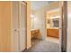 Hallway leading to a full bathroom with wood cabinets, double sinks, and tile flooring at 9093 Sw 91St Cir, Ocala, FL 34481