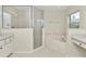 Bright bathroom showcasing a glass-enclosed shower, and a soaking tub beneath a window for a relaxing ambiance at 9859 Sw 45Th Ave, Ocala, FL 34476