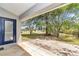 Covered patio with a blue door leading to a spacious backyard and lush greenery at 9859 Sw 45Th Ave, Ocala, FL 34476