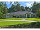 Single-story residence featuring a well-groomed lawn, a circular driveway, and lush surrounding trees at 7939 Se 12Th Cir, Ocala, FL 34480
