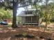 Exterior of quaint home surrounded by mature trees featuring a screened porch and metal roof at 10805 Se 102Nd Pl, Ocala, FL 34472