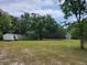 View of property with trees surrounding the home and an additional building on a grassy lot at 10805 Se 102Nd Pl, Ocala, FL 34472