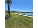 Exterior view of a community pond with a green lawn, a sidewalk, and a palm tree in the foreground at 1114 Brimstone Cir, Winter Haven, FL 33884