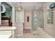A well-lit bathroom features a glass shower, a large tub, and floral wallpaper at 11569 Sw 75Th Cir, Ocala, FL 34476