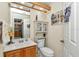 A clean bathroom with a wood cabinet sink, toilet, decorative shelving, and art at 11569 Sw 75Th Cir, Ocala, FL 34476