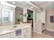 A bathroom vanity with double sinks and floral wallpaper reflects in the large mirror at 11569 Sw 75Th Cir, Ocala, FL 34476
