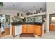 Open kitchen featuring wood cabinets, granite countertops, a dishwasher, and decorative wallpaper at 11569 Sw 75Th Cir, Ocala, FL 34476