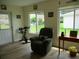 Bright living room with large windows, plush recliner, and light wood-look flooring at 11628 Sw 140Th Loop, Dunnellon, FL 34432