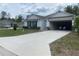 Inviting single-story home featuring a spacious driveway leading to an attached garage, surrounded by well-manicured landscaping at 12 Hickory Course Way, Ocala, FL 34472
