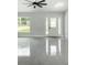 A bright, light-filled living room with modern ceiling fan, front door, and large windows offering natural light at 12180 Se 89Th Ter, Belleview, FL 34420