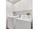 This laundry room features white appliances and upper cabinets providing ample storage space at 1736 Watts Mill Way, The Villages, FL 32162