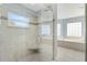 Bright bathroom featuring a glass shower, tiled walls, and a luxurious soaking tub under a window at 17902 Se 115Th Cir, Summerfield, FL 34491