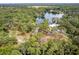 Expansive aerial view of a home nestled among lush trees, near a serene lake and winding road at 19938 Burkitt Rd, Dunnellon, FL 34432
