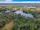 An expansive aerial view of a serene lake surrounded by lush trees and other homes at 19938 Burkitt Rd, Dunnellon, FL 34432