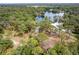 An aerial view showcases a charming home nestled amongst the surrounding trees and a pristine lake at 19938 Burkitt Rd, Dunnellon, FL 34432