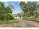 Backyard view features a gentle slope leading to serene water with lush trees in the background at 19938 Burkitt Rd, Dunnellon, FL 34432