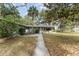 Charming home with stone facade, mature trees, and a long walkway leading to the entrance at 19938 Burkitt Rd, Dunnellon, FL 34432