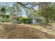 Exterior shot of a light blue home with large windows and mature trees in the background at 19938 Burkitt Rd, Dunnellon, FL 34432