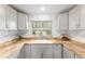 Bright kitchen with wood countertops, white cabinets, and subway tile backsplash at 19938 Burkitt Rd, Dunnellon, FL 34432