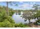 Scenic view of a tranquil lake surrounded by lush trees, showcasing a dock and blue skies at 19938 Burkitt Rd, Dunnellon, FL 34432