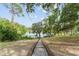 Backyard features a gentle path leading to a serene lake, framed by lush, mature trees at 19938 Burkitt Rd, Dunnellon, FL 34432
