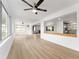 Open living room featuring light hardwood floors, white walls, brick fireplace and an open kitchen at 19938 Burkitt Rd, Dunnellon, FL 34432