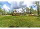 Spacious backyard featuring lush green grass, mature trees, and the exterior of a light tan home at 23964 Nw Falcon Ave, Dunnellon, FL 34431