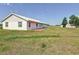 A view of the white home exterior with a lush green lawn and two storage sheds at 258 Nw 122Nd Ave, Oxford, FL 34484