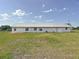 Back exterior view of the home surrounded by a large lawn and blue sky at 258 Nw 122Nd Ave, Oxford, FL 34484