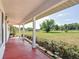 Long covered porch with views of the yard, fencing, and trees at 258 Nw 122Nd Ave, Oxford, FL 34484